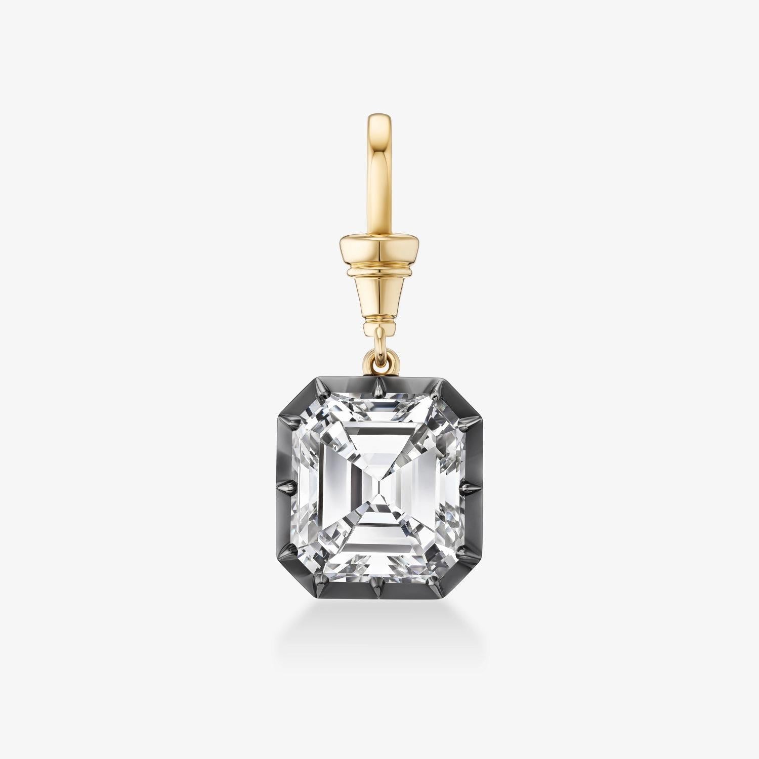 A single drop earring featuring a large, clear, emerald-cut gemstone in a darkened silver or blackened gold setting, suspended from a polished yellow gold bail, shown on a light gray background.