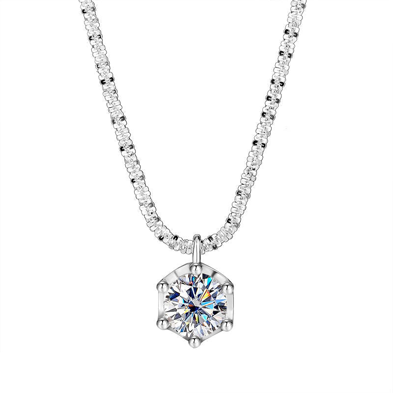 A silver-toned necklace with a hexagonal prong setting featuring a clear round-cut gemstone pendant, shown on a plain white background with the brand name NORELLE in the lower left corner.