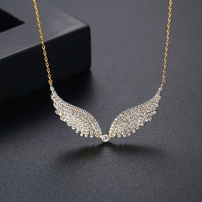 Gold necklace with angel wing design on a dark surface