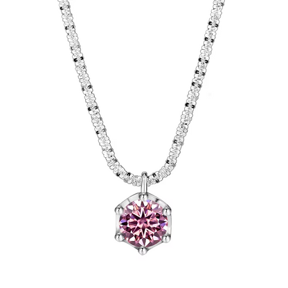 A silver-tone necklace featuring a hexagonal pendant with a faceted pink gemstone, set on a delicate pavé chain. The brand name 'NORELLE' is printed in black at the bottom left, all on a solid white background.