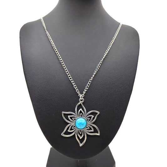 A silver-tone floral pendant necklace with a central turquoise blue stone, displayed on a black jewelry bust against a white background.