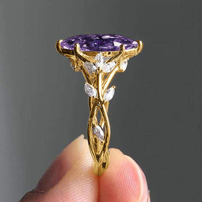 Gold ring with a purple gemstone held by a hand against a dark background