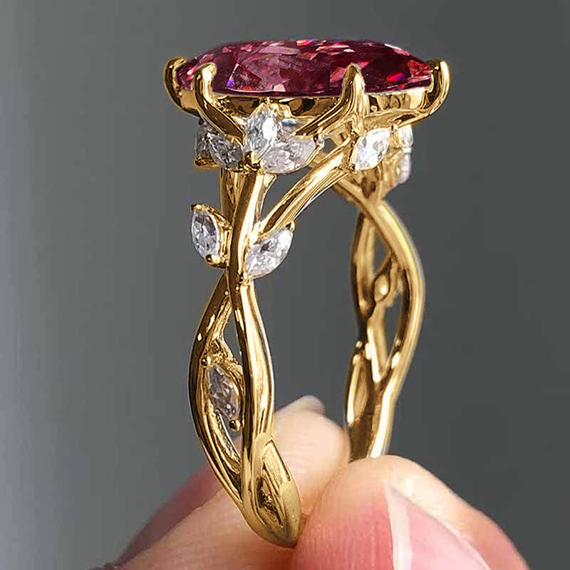 Gold ring with a pink gemstone held by a hand against a gray background
