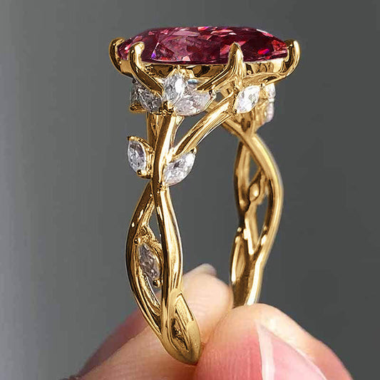 Gold ring with a pink gemstone held by a hand against a gray background