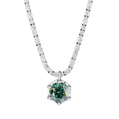 A silver-tone necklace featuring a hexagonal pendant with a faceted green gemstone, set on a delicate pavé chain. The brand name 'NORELLE' is printed in black at the bottom left, against a solid white background.